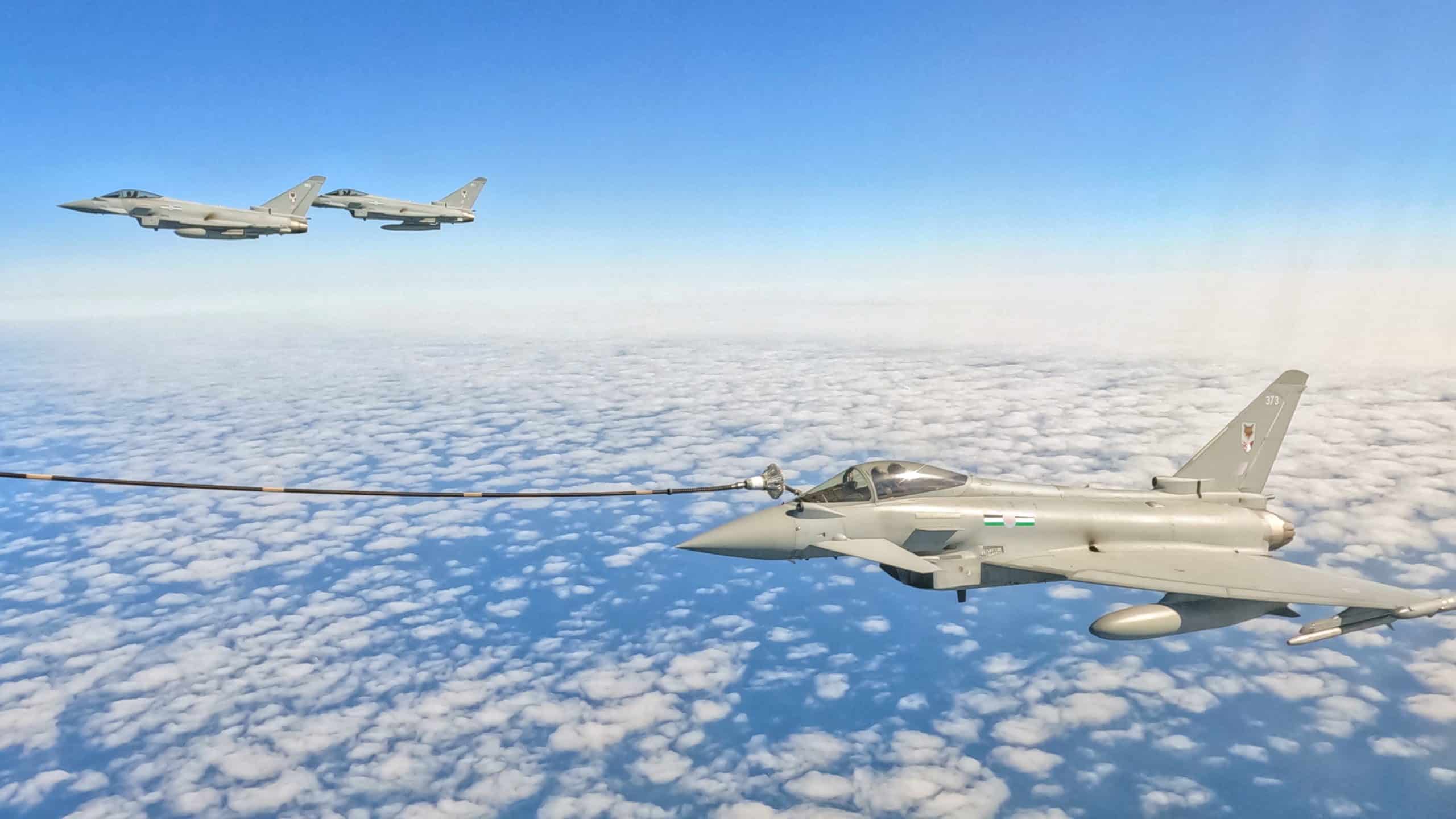 Истребитель RAF Typhoon с присоединенным тросом дозаправляется в воздухе над Северным морем. На заднем плане видны еще два истребителя