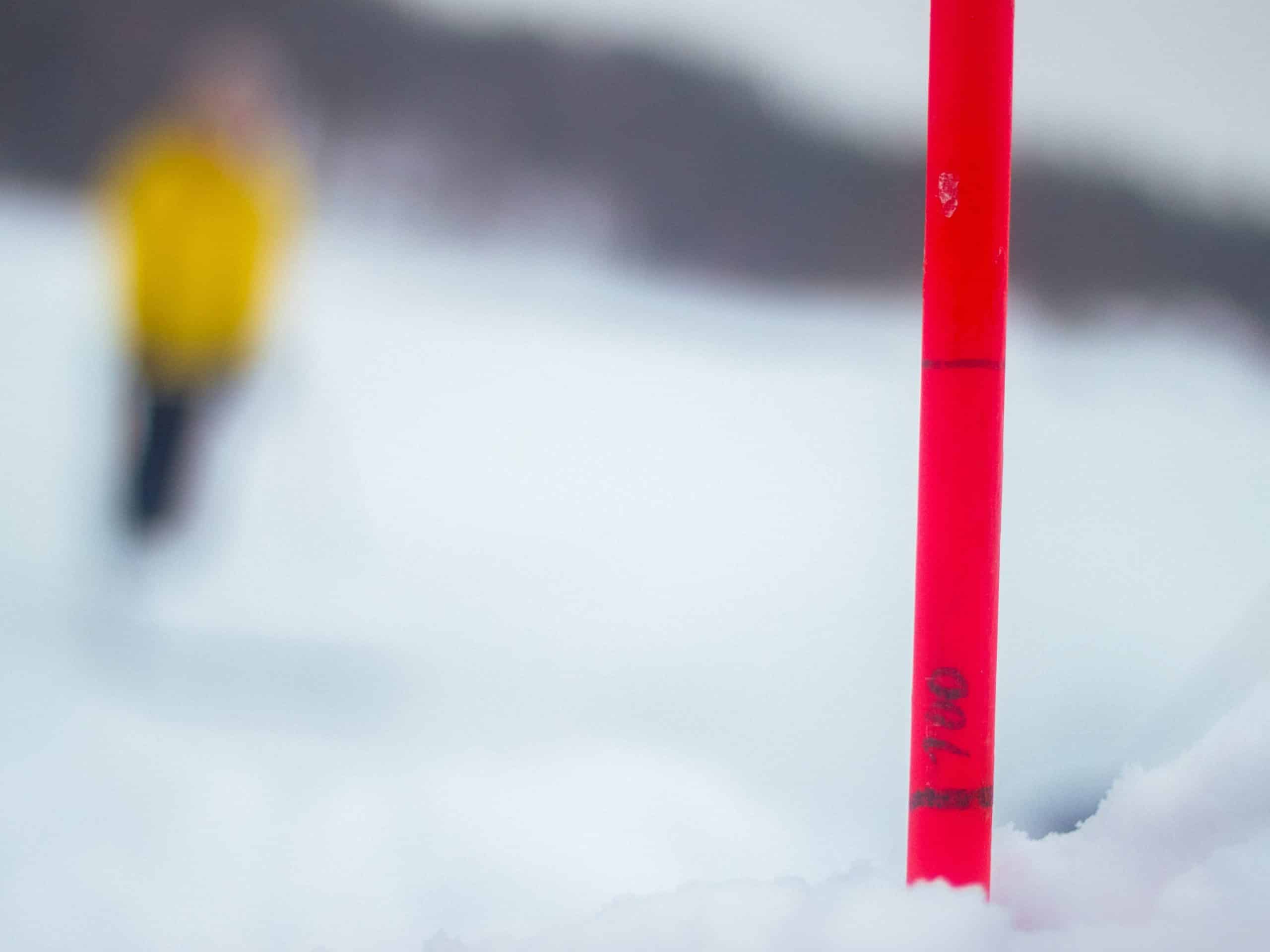 крупный план флуоресцентной палки, отмеченной цифрами в снегу