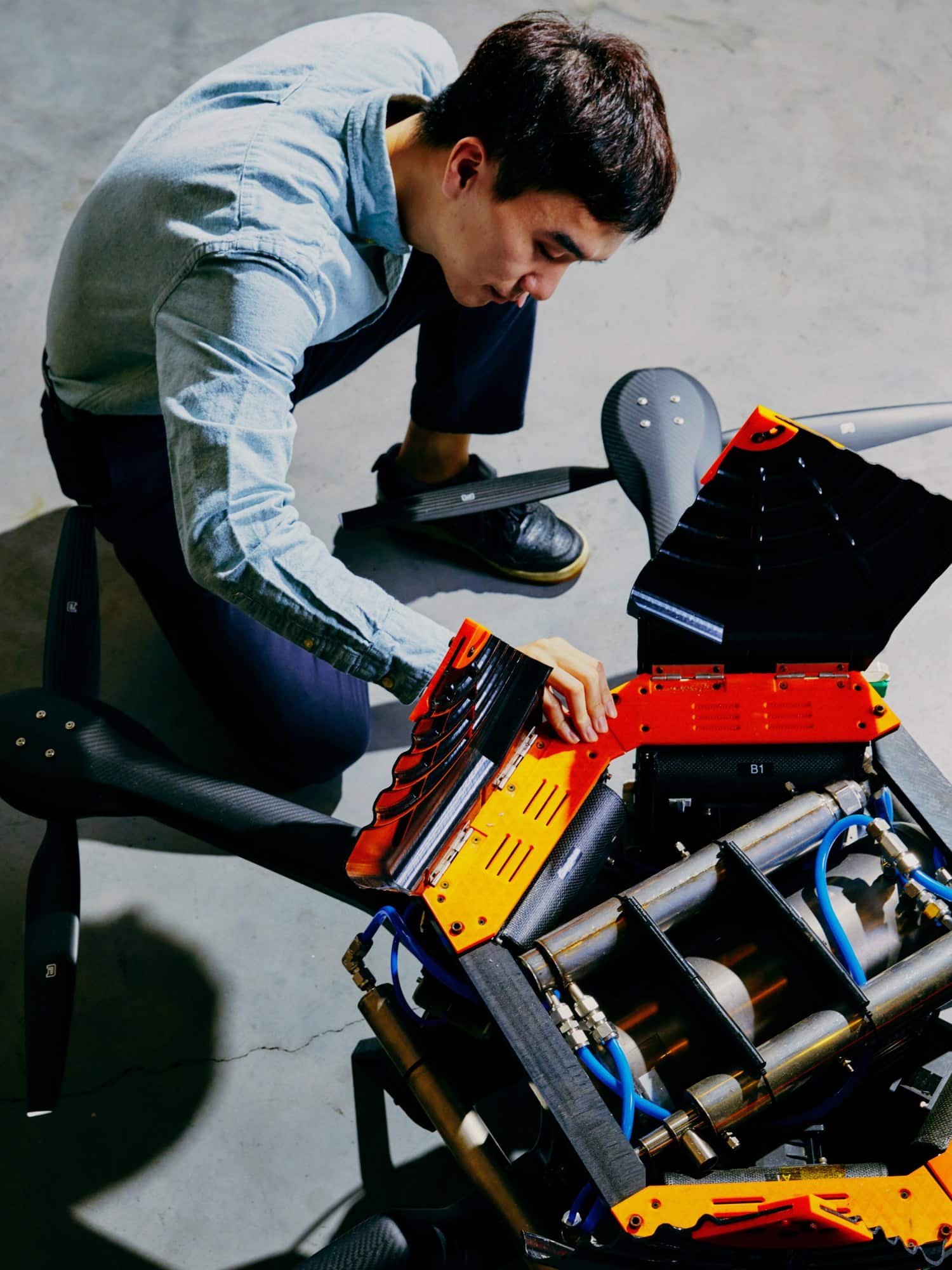 Young Suk Jo crouches on the workroom floor next to a drone