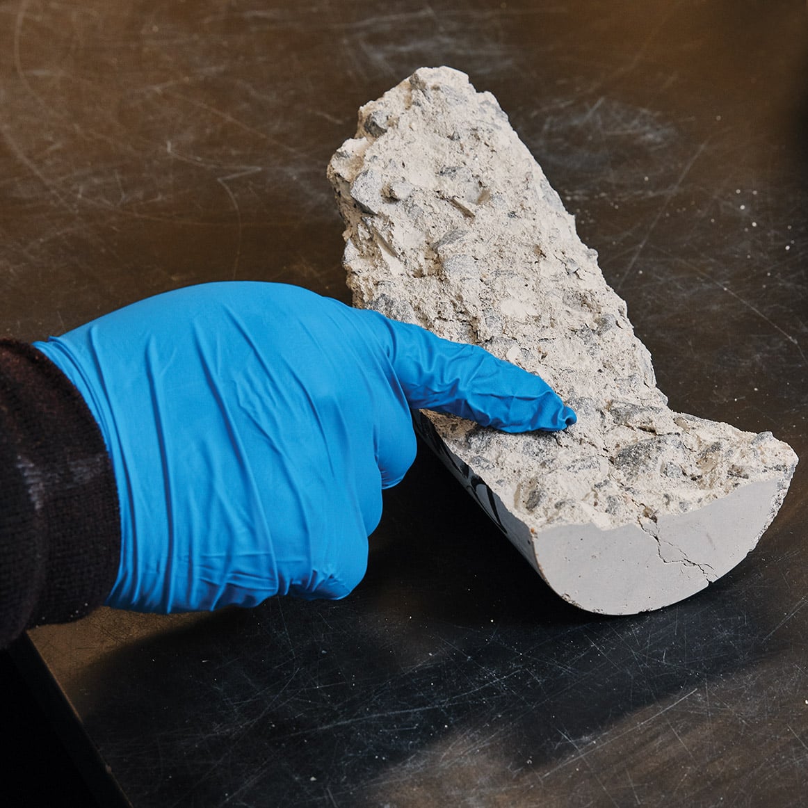 Работник в перчатке указывает в грубый интерьер сломанного цементного цилиндра