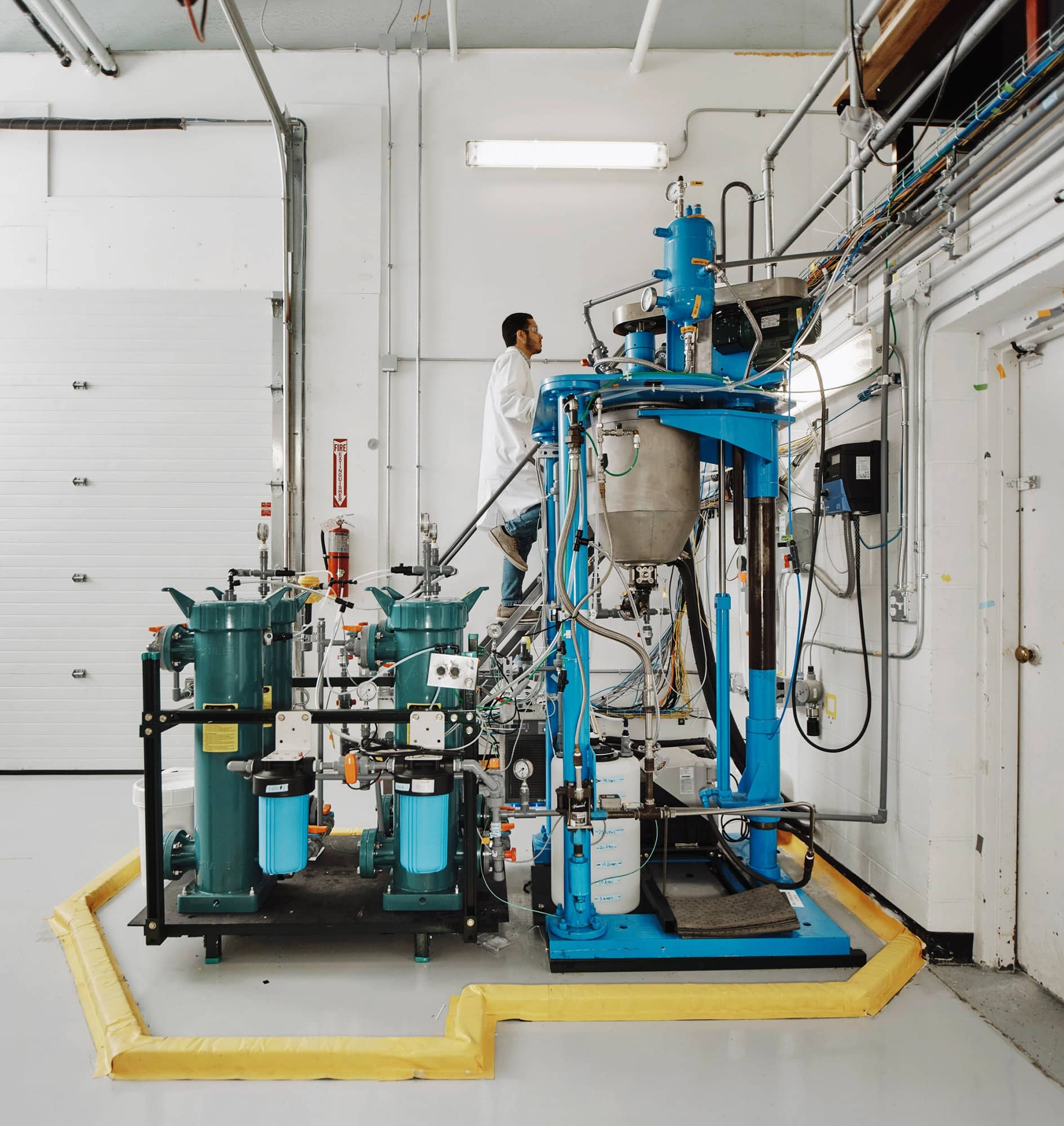 Работник использует переносную лестницу, чтобы добраться до вершины машины