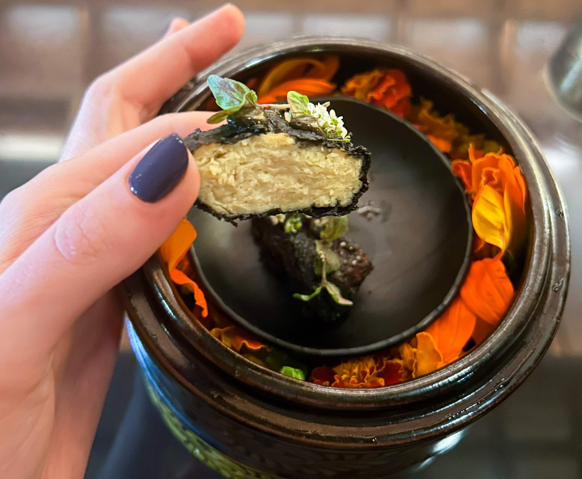 a hand holding the cultivated chicken piece up for the camera to see the texture